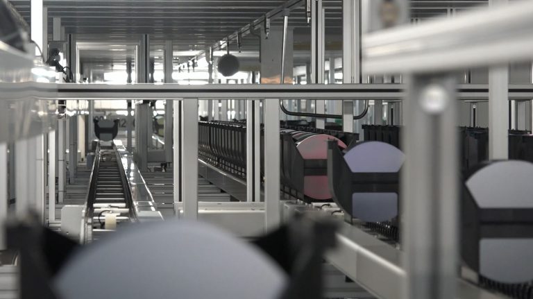 Many 200mm wafer cassettes move on roller conveyors through a semiconductor factory