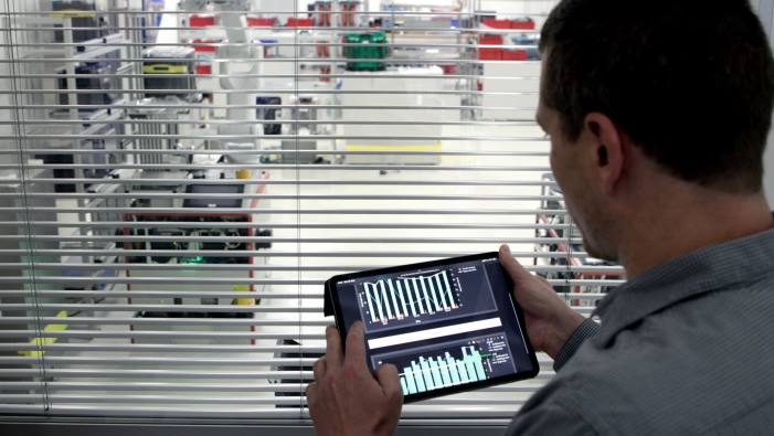 Mann sichtet Daten auf Tablet mit mobilen Roboter im Hintergrund