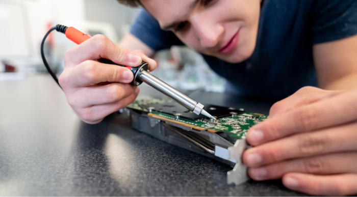 Junger Mensch lötet an elektronischer Baugruppen bzw. Leiterplatte